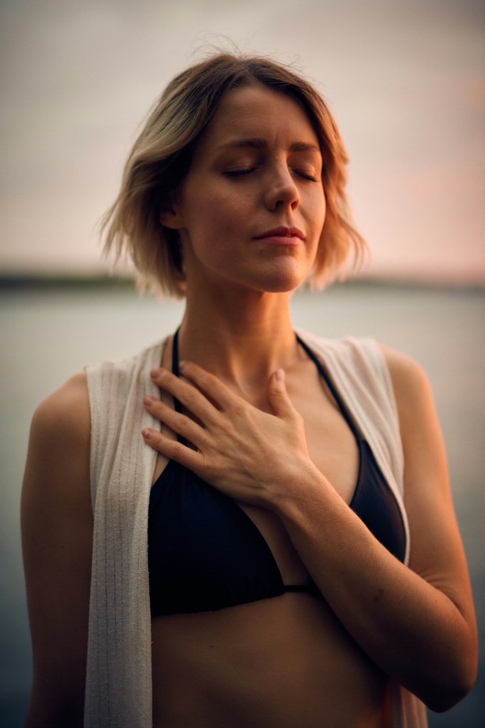 Una donna con la mano sul cuore, in ascolto del respiro.